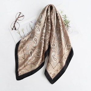 Detailed view of silk-texture paisley scarf with elegant brown tones and black border