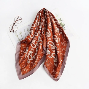 Detailed view of paisley pattern silk scarf with mauve border on a white lifestyle background