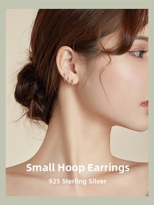 Close-up of 925 sterling silver rainbow gradient small hoop earrings worn on female ear