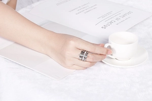 Close-up of a silver stainless steel layered ring with Roman numerals and a cross charm