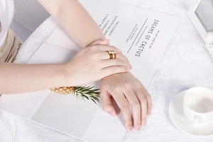 Close-up of dual-tone hollow Roman letter shell ring on model's hand with aesthetic decor