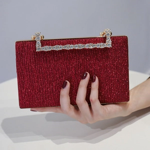 Detailed view of a red glitter evening clutch with gold hardware and rhinestone handle