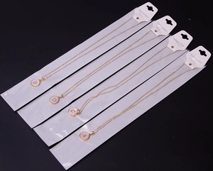 Detail of four golden stainless steel initial necklaces with A B C D round pendants