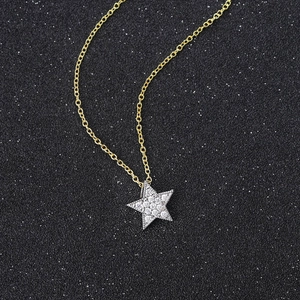 Macro detail of gold star pendant with zircon stones on a refined gold chain