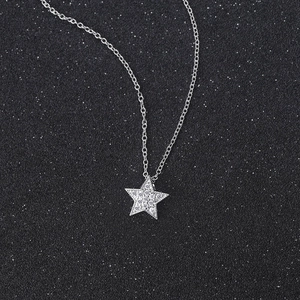 Minimalist silver star pendant necklace with cubic zirconia on black starry background