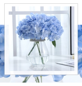 Blue artificial hydrangea flowers in a clear glass vase with twine cord detail