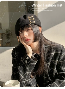 Close-up of black wool beret featuring stylish gold paperclip metal accents on side