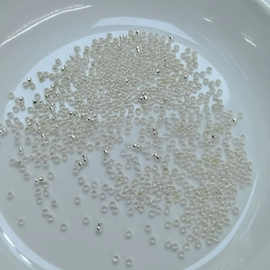 Macro shot of silver small cylindrical crimp beads for jewelry making in a white ceramic dish
