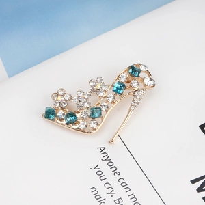 Close-up of high heel brooch with white rhinestones and blue crystals on gold alloy