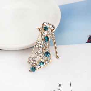 Detailed close-up of high heel brooch with peacock blue rhinestones and gold plating