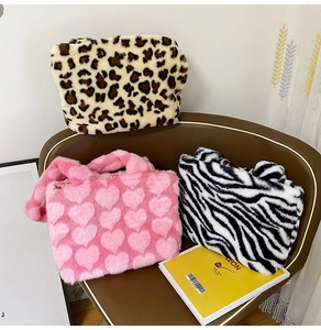 Detailed pile of plush leopard, pink heart, and zebra pattern tote bags on a chair