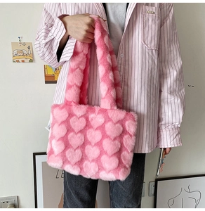 Detailed plush texture of pink heart pattern faux fur tote bag held by a model