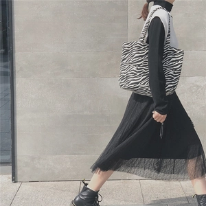 Outdoor street style view of a zebra print canvas tote bag carried by a fashion model
