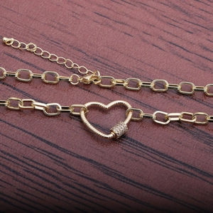 Collana hip hop dorata con ciondolo a cuore e zirconi su sfondo in legno scuro e naturale