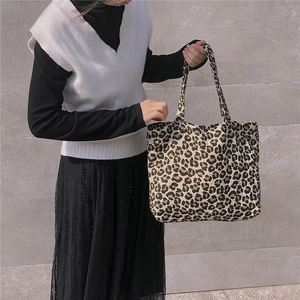 Detail of a large leopard print canvas tote bag carried by a model on a shoulder