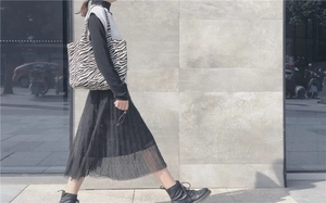 Outdoor street view of a woman wearing a black and white zebra print canvas tote bag
