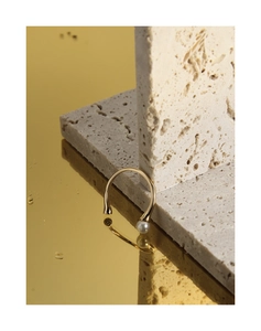Detail of elegant gold-tone S925 silver ring with a lustrous white shell pearl on a rock