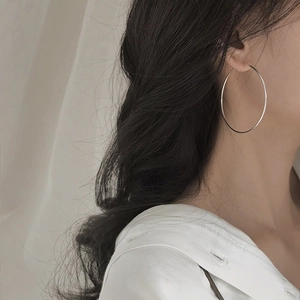Close-up of a model wearing large silver s925 sterling silver hoop earrings in minimalist style