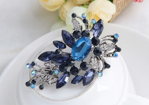 Détail macro d'une broche vintage en cristal bleu avec gravure florale argentée
