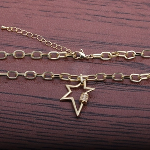 Gold paperclip chain necklace with a hollow star pendant and zircon details on wood