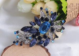 Détail d'une broche vintage en alliage argenté avec cristaux bleus sur fond de bois