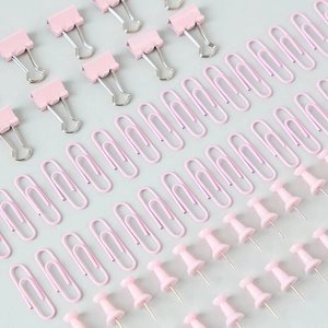 Set di cancelleria rosa con fermagli, graffette e puntine in una disposizione ordinata