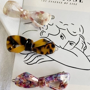 Close-up of three acetate bow hair clips in marble, tortoiseshell and mosaic patterns