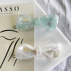 Detail of elegant acetate bow hair clips in mint green and ivory with marble texture