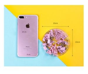 Vista dall'alto di graffette rosa e clip fermafogli in una scatola rotonda rosa
