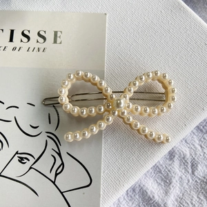 Detail of cream pearl bow hair clip on an artistic background with Matisse card