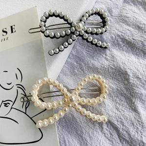 Detail of elegant acetate hair clips with pearls and bows in black and cream