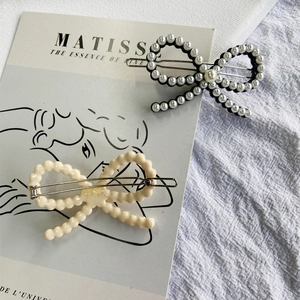 Two elegant bow hair clips with white pearls on a minimalist artistic background card