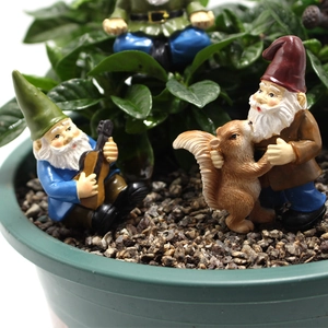 Detailed view of colorful resin fairy garden gnomes and squirrel statues in a flower pot