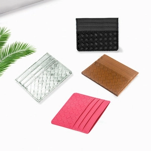 Flat lay of woven PU leather card holders in black, silver, brown, and pink with green leaf deco