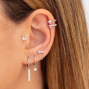 Close-up of silver zircon butterfly ear cuff and dainty chain stud earrings on model