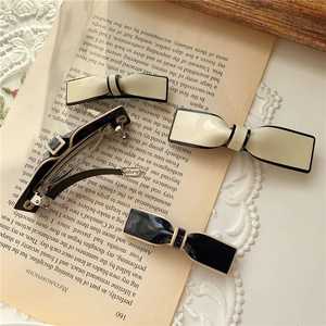 Detail of chic resin bow hair clips in black and cream with contrast piping on lace