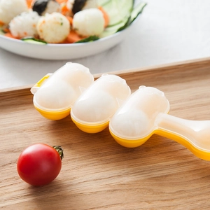 Three-grid plastic rice ball maker on wooden tray with food garnishes for home cooking