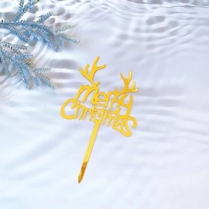 Golden acrylic Merry Christmas cake topper with reindeer antlers on white textured fabric