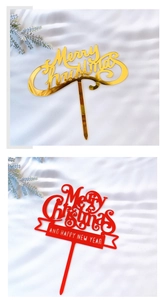 Close-up of gold and red acrylic Merry Christmas cake toppers on white silk fabric