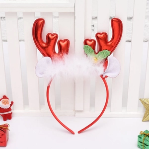 Detail of red reindeer horn headband with white feathers and festive bells on white wooden background
