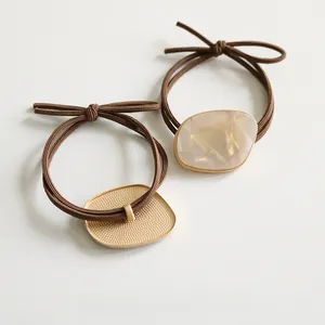 Detail of coffee elastic hair tie with bow and faux mother-of-pearl metal pendant