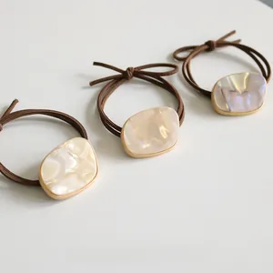 Close-up of elegant brown hair ties with iridescent resin charms and gold metal details