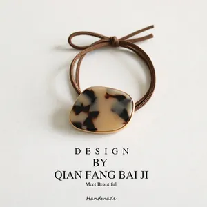 Elegant tortoiseshell acetate hair tie with gold trim on a soft leather surface