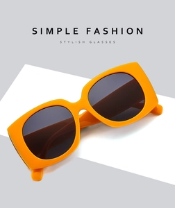 Macro view of bright orange oversized sunglasses frame with glossy resin texture