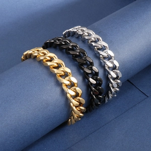 Trois bracelets gourmettes en or, noir et argent sur un support d'affichage bleu