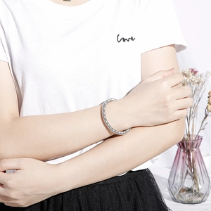 Modern silver stainless steel snake pattern bracelet worn by a model in a minimal setting