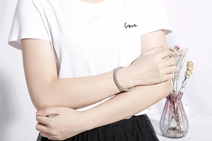 Detail view of silver textured bangle showing circular pattern on female model wrist