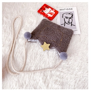 Detail of plush lamb wool kids bag with soft grey pom-poms and shiny gold star