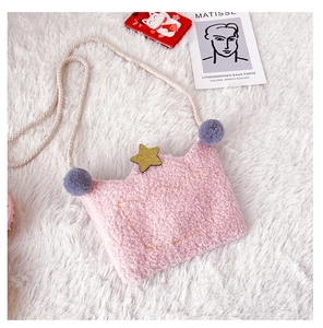 Detail view of a pink plush crown crossbody bag with gold stars and grey fur ball accents