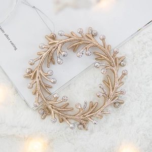 Sparkling gold and silver glitter Christmas wreath ornament hanging on a white plush background
